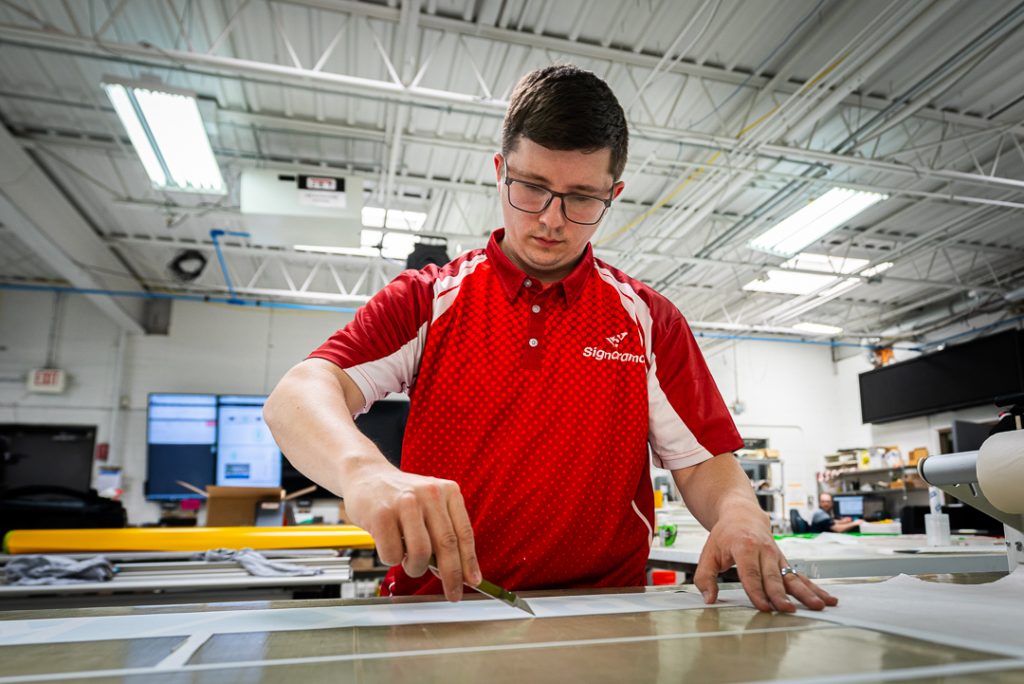 Young man at work in a signage facility