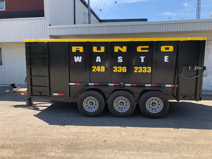 Black dumpster on wheels with yellow lettering