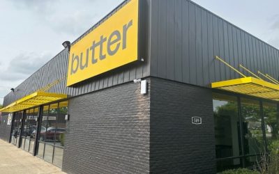 Exterior photo of a black brick building with a yellow sign that says "butter."