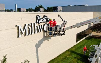 Two men in a cherry picker installing a building sign