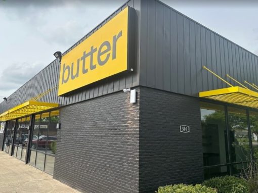 Exterior photo of a black brick building with a yellow sign that says "butter."