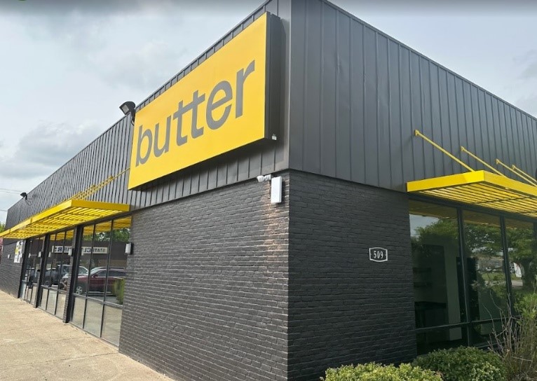 Exterior photo of a black brick building with a yellow sign that says "butter."
